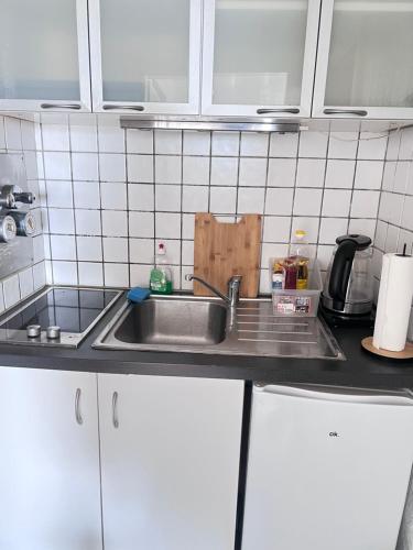 eine Küchentheke mit einer Spüle und weißen Schränken in der Unterkunft Ferienwohnungen in Köln2201 in Köln