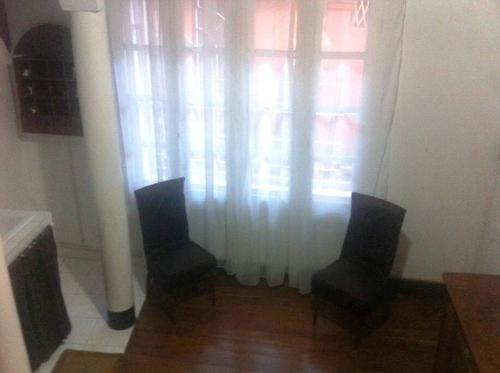duas cadeiras em frente a uma janela com cortinas em Au coeur de Tana, vue sur le Palais de la Reine, en securité em Antananarivo