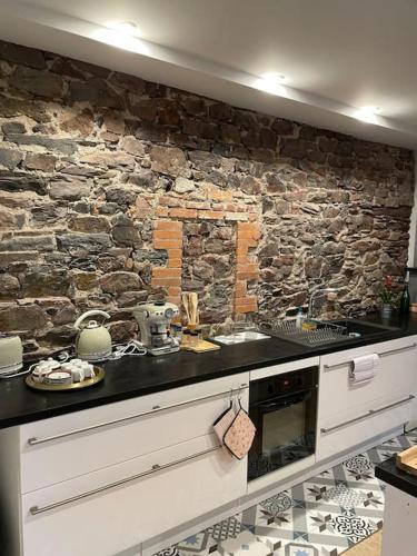 une cuisine avec un mur en pierre et un comptoir dans l'établissement La Maison Cahour, à Redon