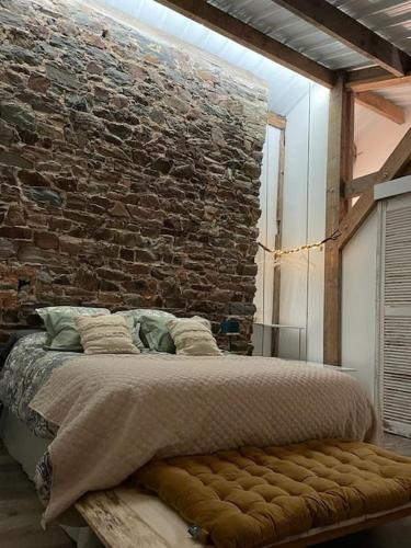 un lit dans une chambre avec un mur de briques dans l'établissement La Maison Cahour, à Redon