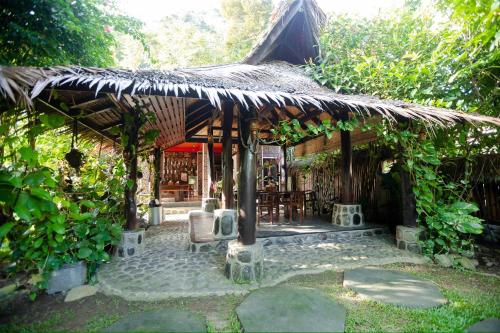 a pavilion with a table and chairs in a garden at Green Travelodge Bukit Lawang in Bukit Lawang