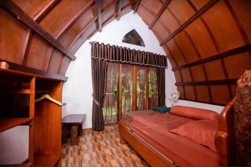 Green Travelodge Bukit Lawang في بوكيت لاوانج: غرفة نوم بسرير ونافذة كبيرة