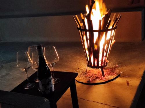 a bottle of wine and two wine glasses and a candle holder at Etoko Farm Camp in Uis