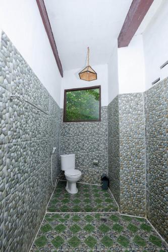 a bathroom with a toilet and a window at Green Travelodge Bukit Lawang in Bukit Lawang