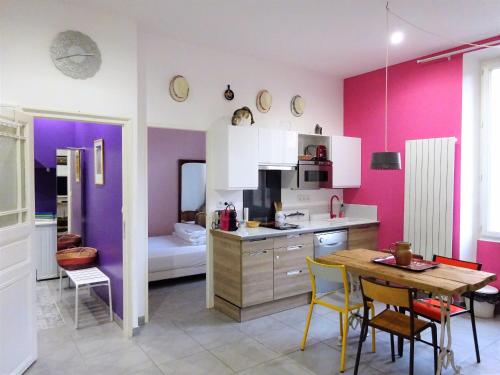 - une cuisine avec des murs violets, une table et des chaises dans l'établissement Vieux Port Panier Jardin, à Marseille