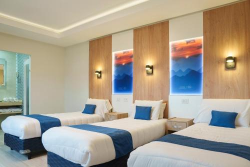 a hotel room with three beds with blue pillows at Cabañas Tierra Mistica in Ushuaia