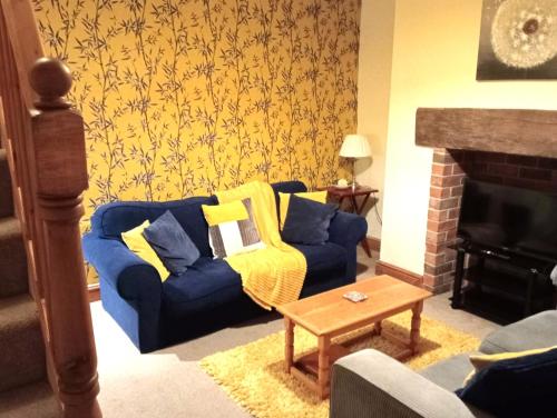 a living room with a blue couch and a fireplace at Bwthyn Bach (Tiny Cottage) in Wrexham