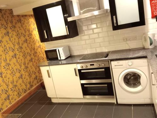 a kitchen with a stove and a washing machine at Bwthyn Bach (Tiny Cottage) in Wrexham