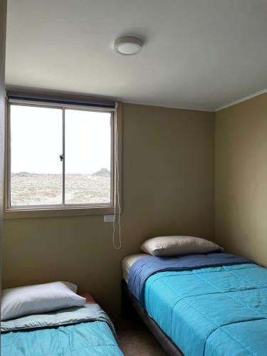 a bedroom with two beds and a window at Entre Dunas y Caracolas in Punta de Choros