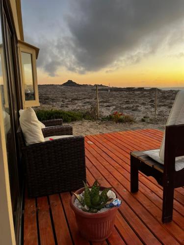 a wooden deck with a couch and a chair on a patio at Entre Dunas y Caracolas in Punta de Choros