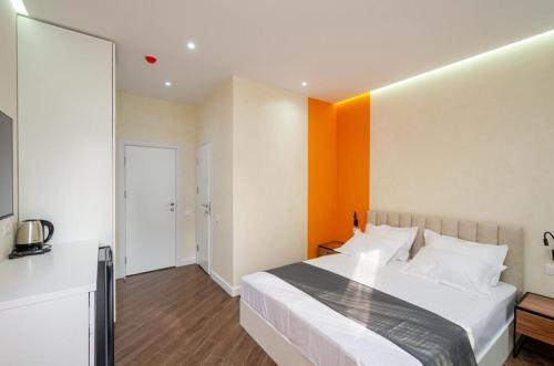 a bedroom with a large bed with an orange wall at Latorre Hotel in Yerevan