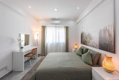 a bedroom with a large bed and a desk at Kition City Apartments - Central Location in Larnaca