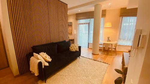 Una sala de estar con un sofá negro y una mesa. en DO Apartments, en Druskininkai