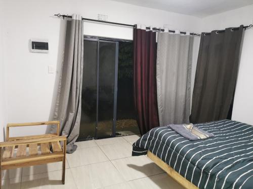 1 dormitorio con 1 cama y una ventana con cortinas en Northside beach lodge, en Vilanculos