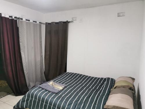 1 dormitorio con 1 cama con sábanas y cortinas a rayas en Northside beach lodge, en Vilanculos