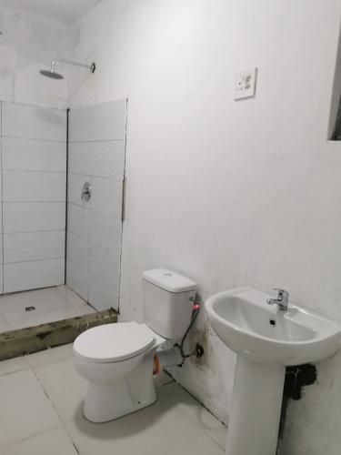 a white bathroom with a toilet and a sink at Northside beach lodge in Vilanculos