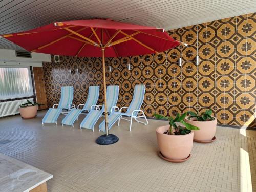 a group of chairs and an umbrella in a room at FeWo Inselblick mit Schwimmbad - Horumersiel in Horumersiel