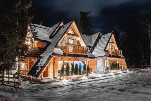 a log cabin in the snow at night at Brzozowa Osada - Premium Chalets Zakopane in Zakopane