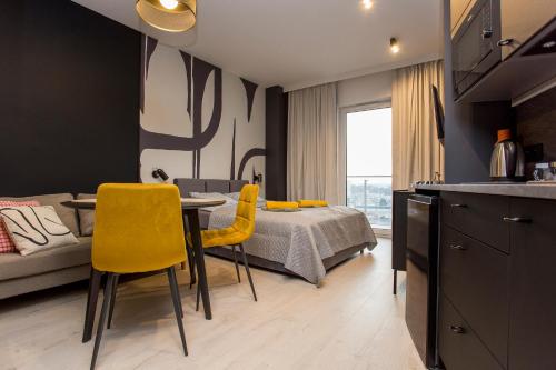 een keuken en een slaapkamer met een tafel en gele stoelen bij Urban Jungle apartament Delta in Białystok