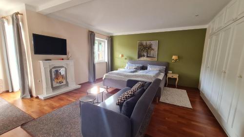 a bedroom with a bed and a couch and a fireplace at Kaiser's Landhaus in Schliersee