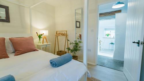a bedroom with a white bed with a blue towel on it at Ty Cwyfan in Aberffraw