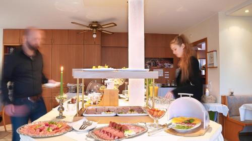 two people standing in a kitchen with a table with food at Hotel Schweizerhof in Böbingen an der Rems