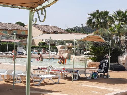 une piscine avec des chaises et des parasols et des gens dans l'eau dans l'établissement Villa Prestige côté calme du domaine de vacances - 8 pers 4 ch 2 sdb 120m2, à Vidauban