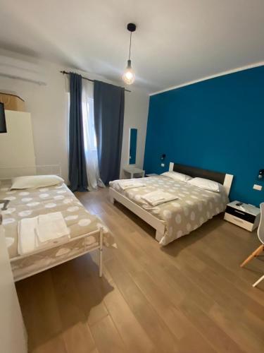 a bedroom with two beds and a blue wall at VILLA MANIVA in Ginosa Marina
