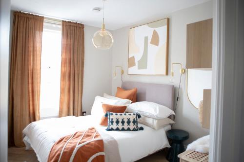 a bedroom with a bed with orange and white pillows at 1 Bed Apartments - Central Bath in Bath