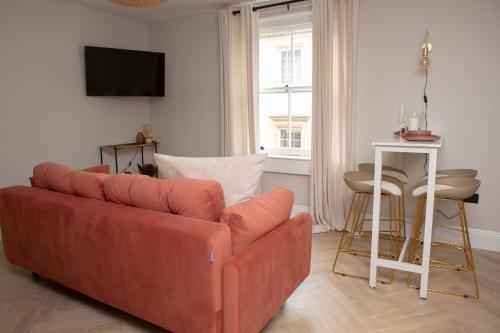 a living room with a red couch and a table at Broad Street Apartments - Central Bath in Bath
