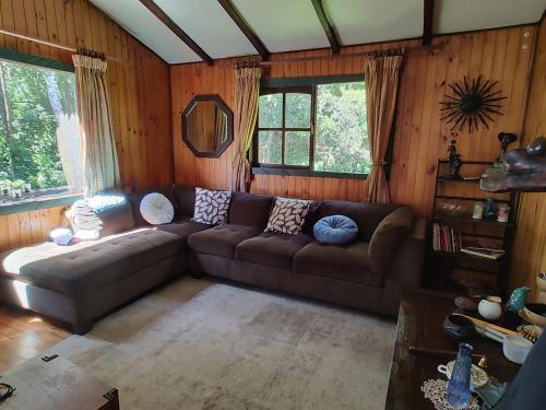 uma sala de estar com um sofá castanho e janelas em Casa o habitacion en carretera austral em Puerto Montt