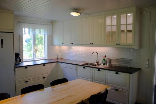 a kitchen with white cabinets and a wooden table at Scoutstugan in Falun