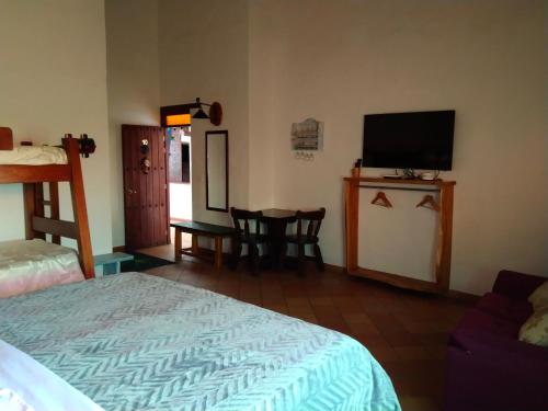 a bedroom with a bed and a tv and a table at Hotel El Peregrino De La Villa in Villa de Leyva