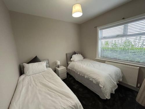 a bedroom with two white beds and a window at Cosy yet spacious bungalow in Saughall
