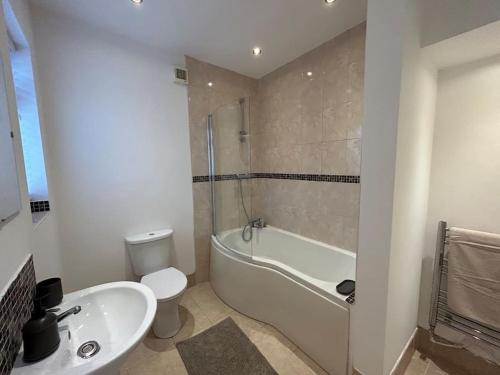 a bathroom with a tub and a toilet and a sink at Cosy yet spacious bungalow in Saughall
