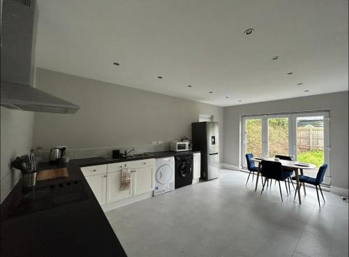 a kitchen with a stove and a table with chairs at Cosy yet spacious bungalow in Saughall