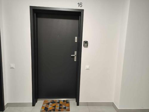 una puerta negra en una habitación con suelo a cuadros en Nova Town Apartament, en Stargard