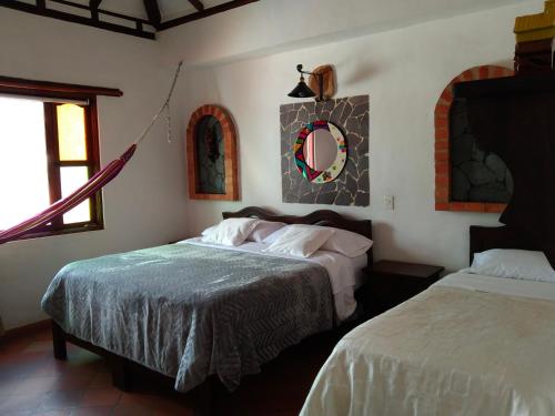 a bedroom with two beds and a mirror on the wall at Hotel El Peregrino De La Villa in Villa de Leyva