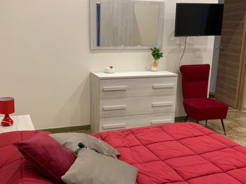 una camera con letto rosso e cassettiera di La Mimosa Case Vacanze a Marsala
