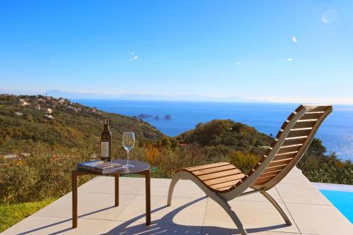 una mesa y una silla con una botella y una copa de vino en Villa Jarito, en SantʼAgata sui Due Golfi