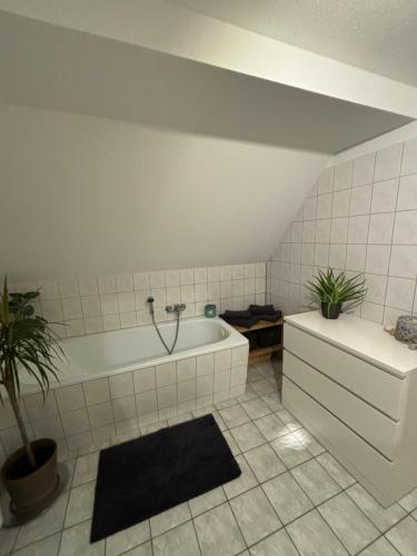 a white bathroom with a tub and a plant at Ferienwohnung „Ruppbergblick“ in Zella-Mehlis