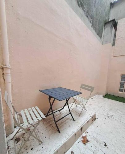 une table et deux chaises assises à côté d'un mur dans l'établissement Studio - Centre Ville - Terrasse, à Agen