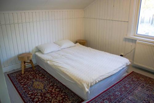 een slaapkamer met een bed met 2 kussens en een tapijt bij Bagarstugan in Falun