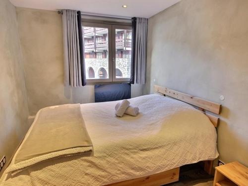 a bedroom with a bed with a stuffed animal on it at Bel appartement cosy de 50m² pour 4 pers, pied des pistes Méribel Mottaret avec terrasse et parking - FR-1-411-913 in Les Allues