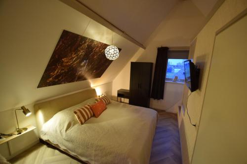 a small bedroom with a bed and a television at Hotelkamer de Loft in Anjum
