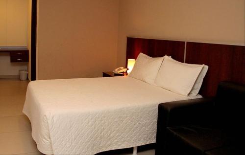 a bedroom with a white bed with a phone and a chair at HOTEL G&EMP Rador BARRANCA in Barranca