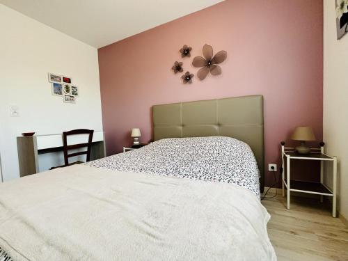 une chambre avec un lit blanc et un mur rose dans l'établissement Appartement recent quartier des Nouettes avec parking, à Les Sables-dʼOlonne