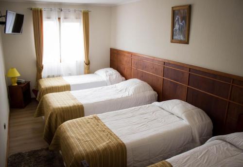 a hotel room with three beds and a window at Hotel Terrazas del Mar in Llanquihue