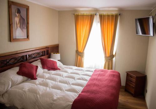 a bedroom with a large white bed with red pillows at Hotel Terrazas del Mar in Llanquihue