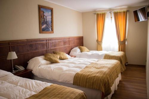a hotel room with three beds and a window at Hotel Terrazas del Mar in Llanquihue